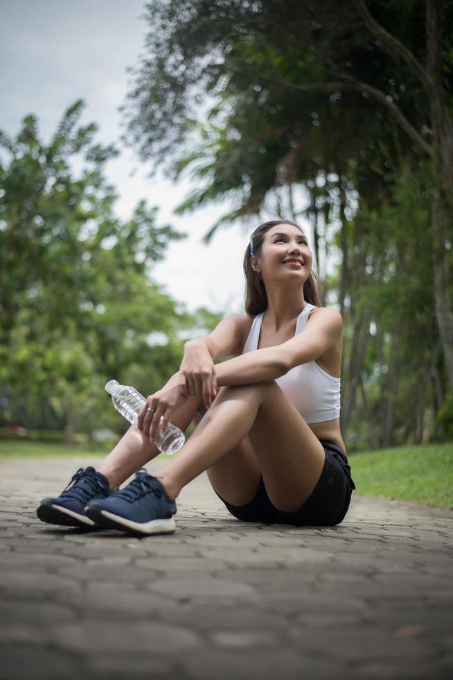 Young sporty woman sits at the park after a jog photo