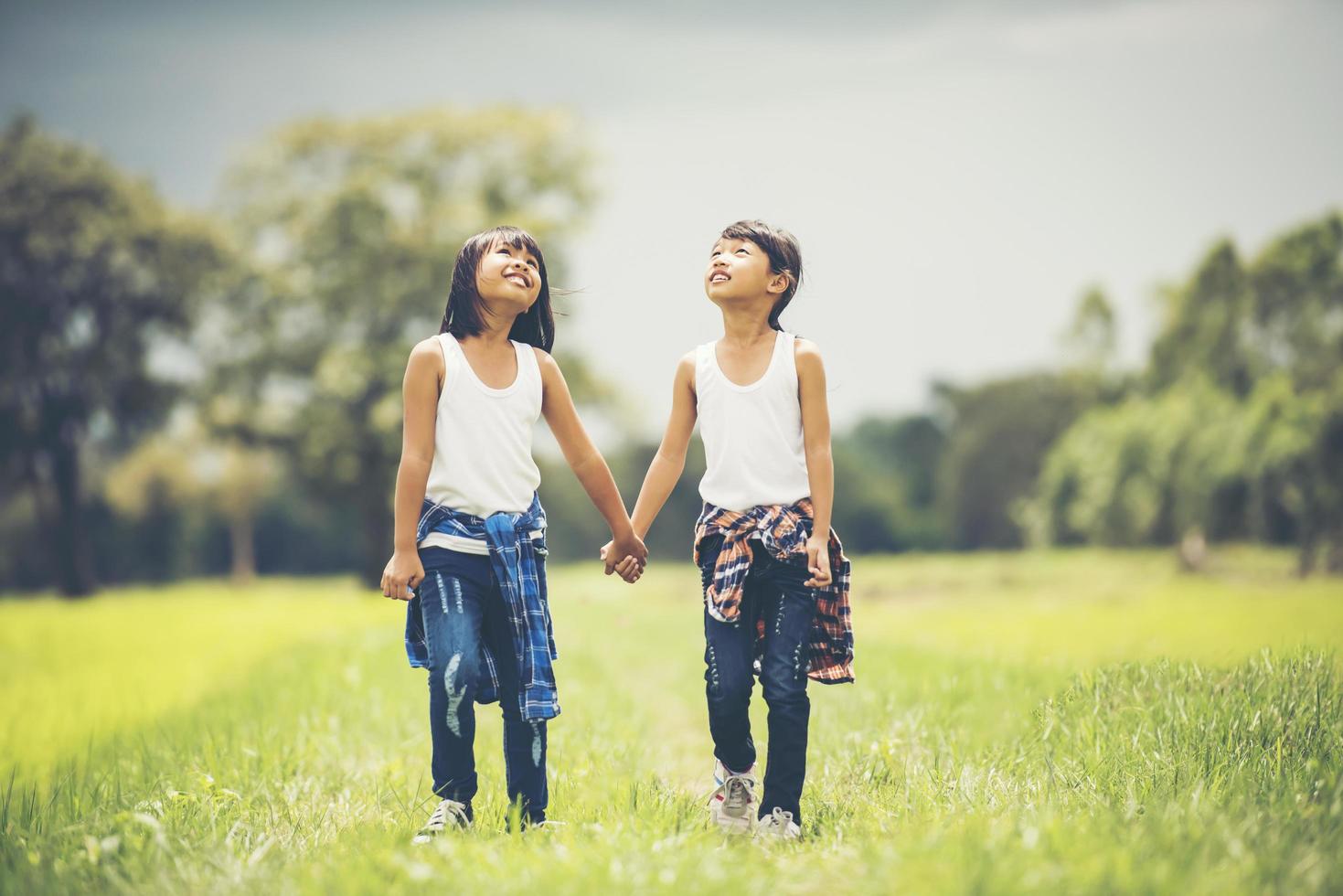 Two little girls holding hands in the park photo