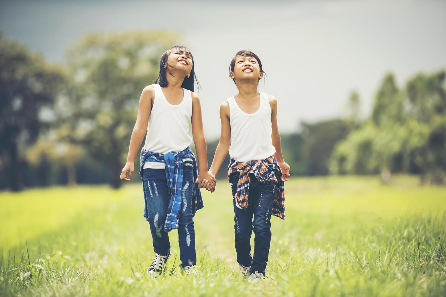 Two little girls holding hands in the park photo