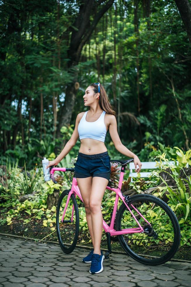 retrato de una mujer con una bicicleta rosa en el parque foto