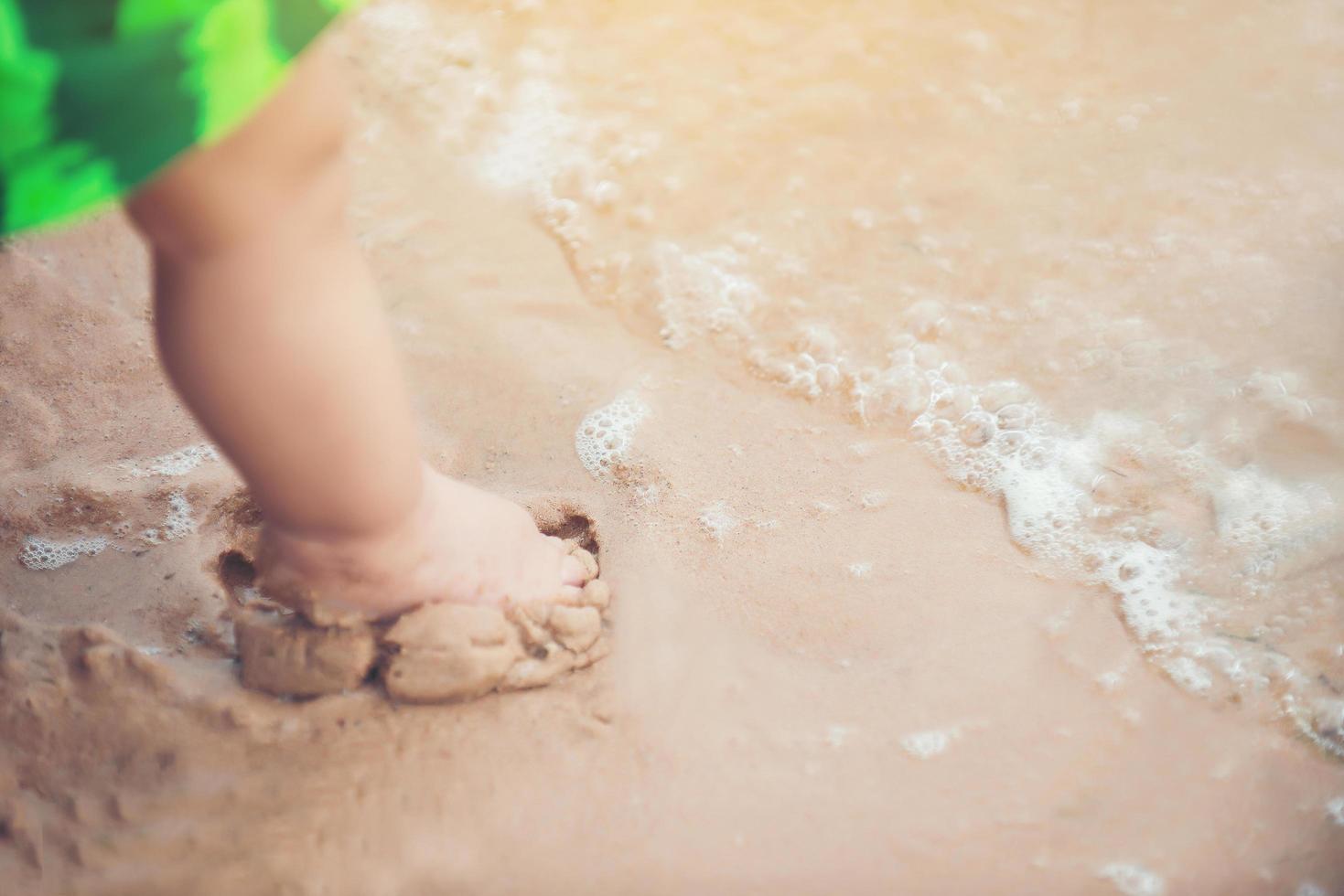 piernas de un niño de pie en la playa foto