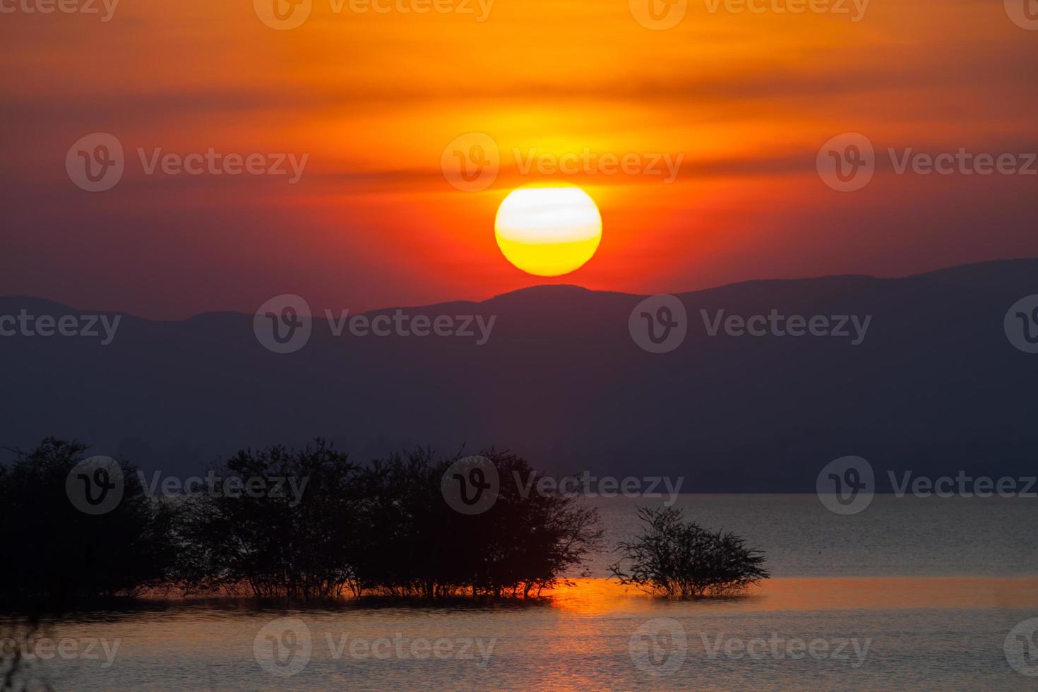 Colorful sunset over trees and water photo