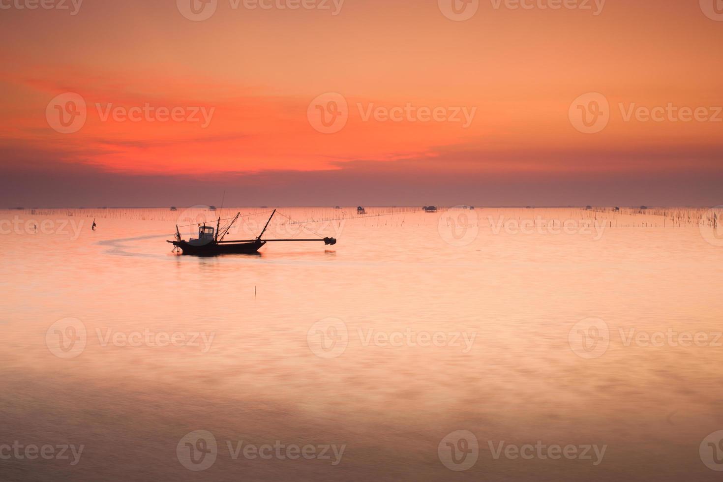 silueta de un barco en el agua al atardecer foto