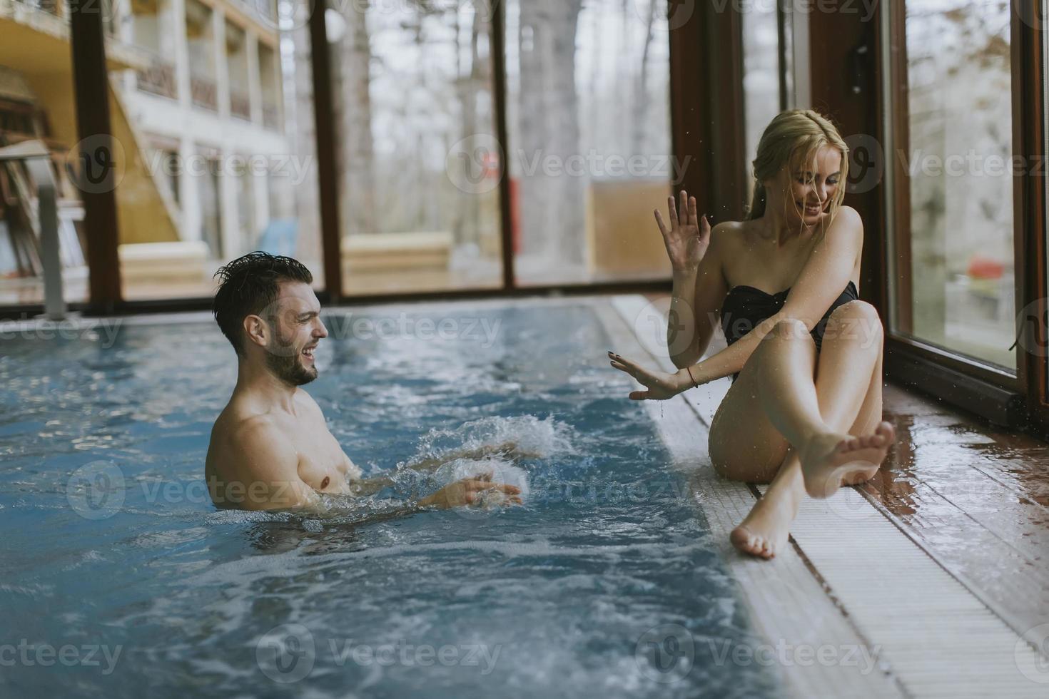 Young couple relaxing on the poolside of interior swimming pool photo