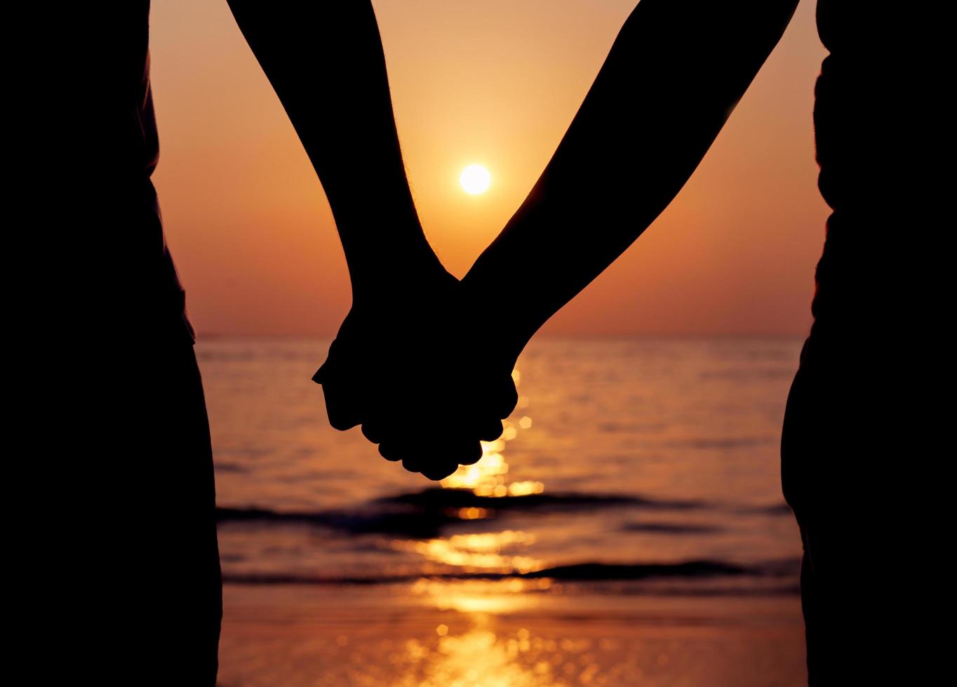 Silhouette of a couple holding hands at sunset photo