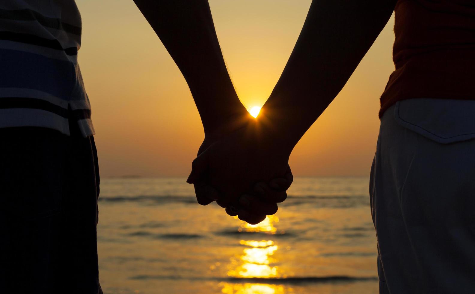 pareja tomados de la mano al atardecer foto