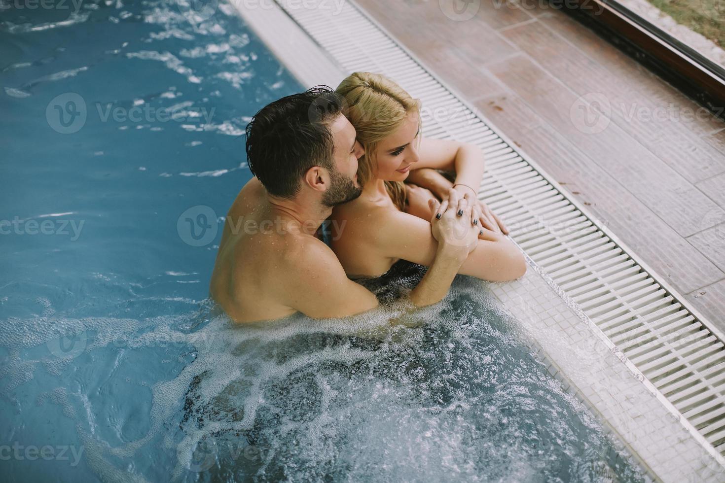 Pareja joven relajándose en la piscina de la piscina interior foto