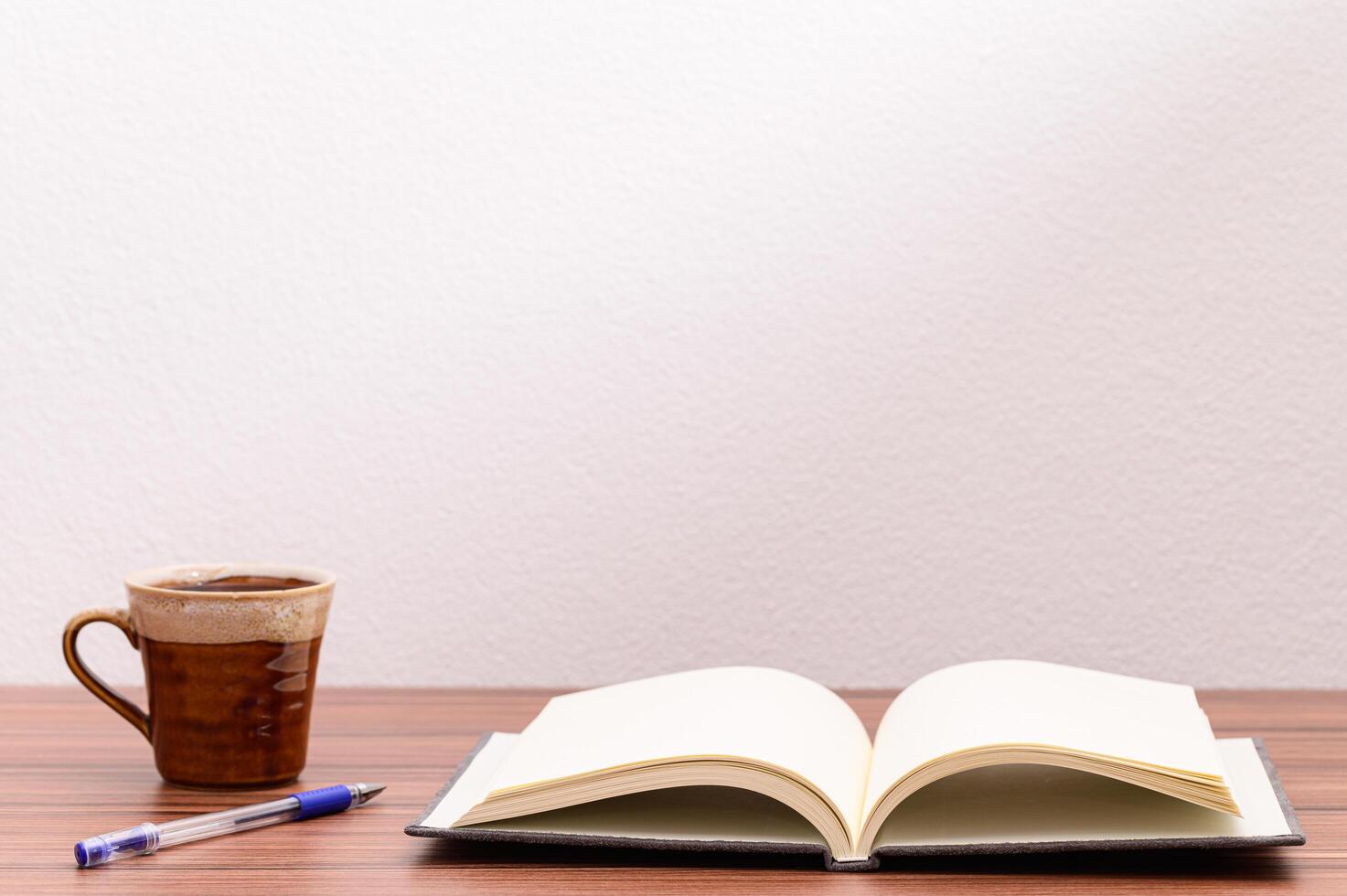 taza de café y cuaderno vacío sobre la mesa foto