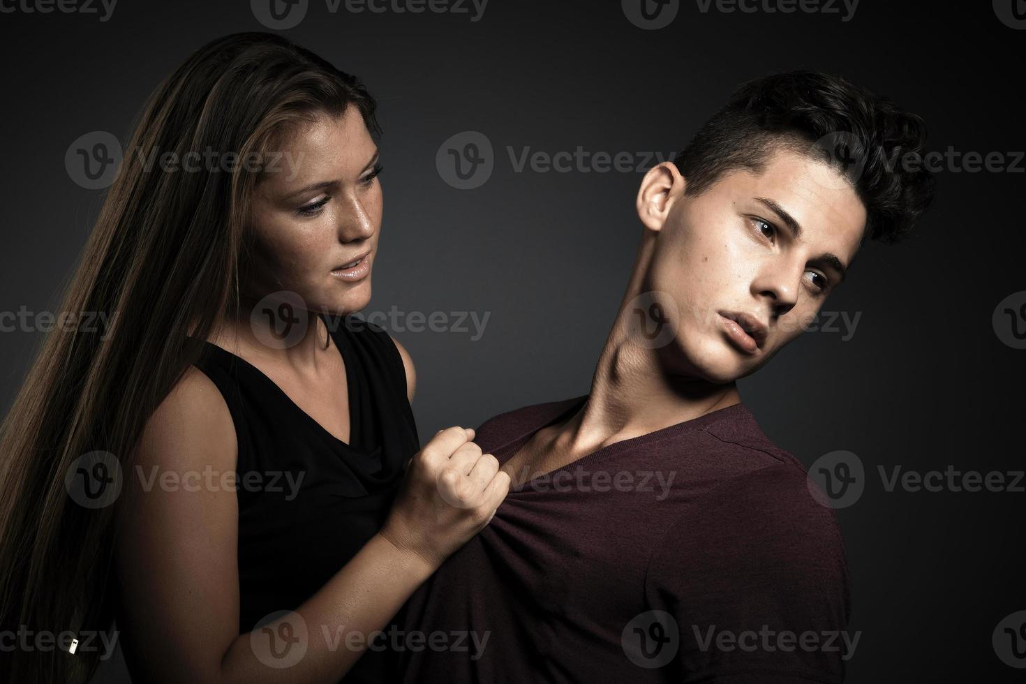 Retrato de una hermosa joven pareja feliz contra un fondo gris oscuro foto