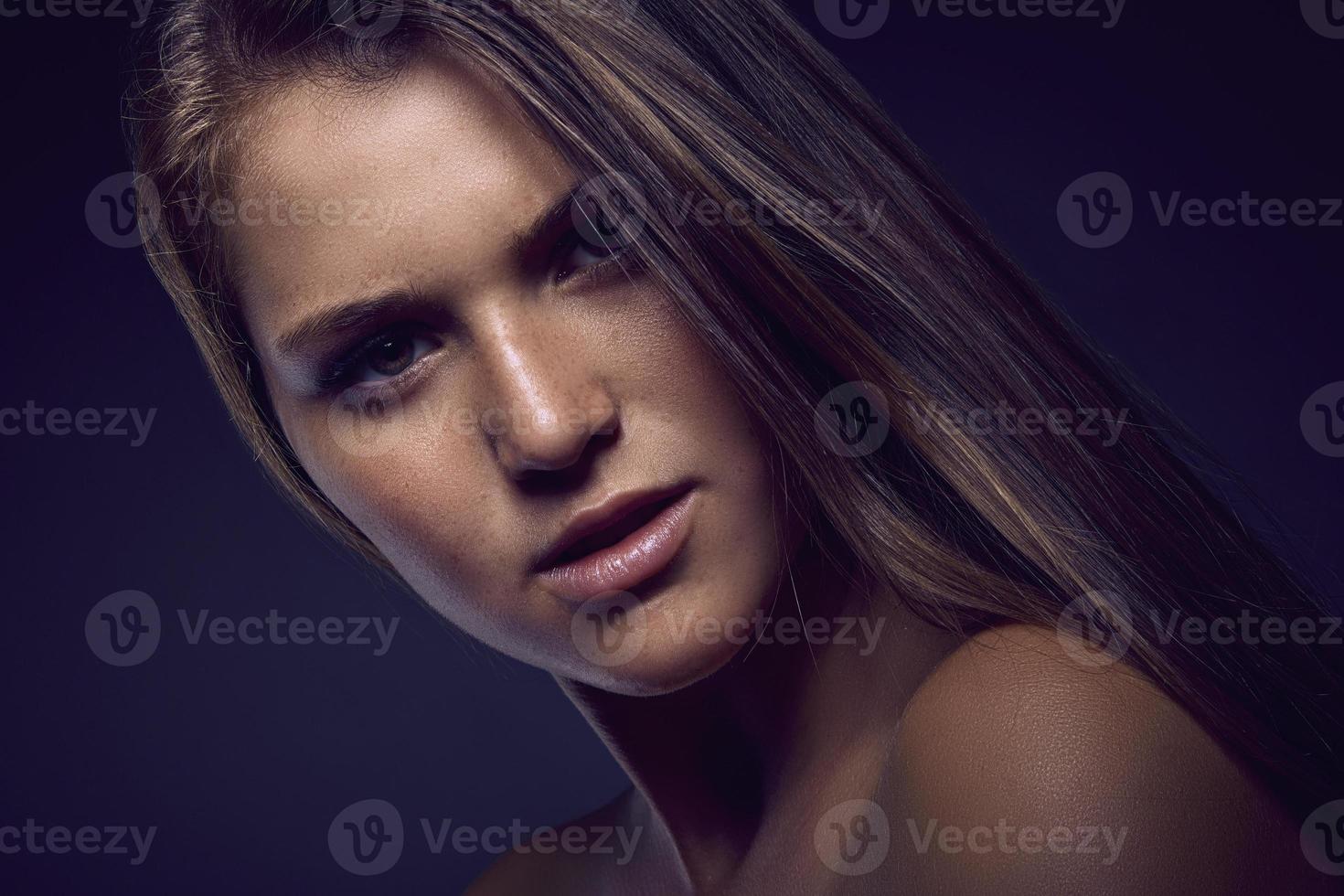 Beauty portrait of a young sexy woman against a dark blue background photo