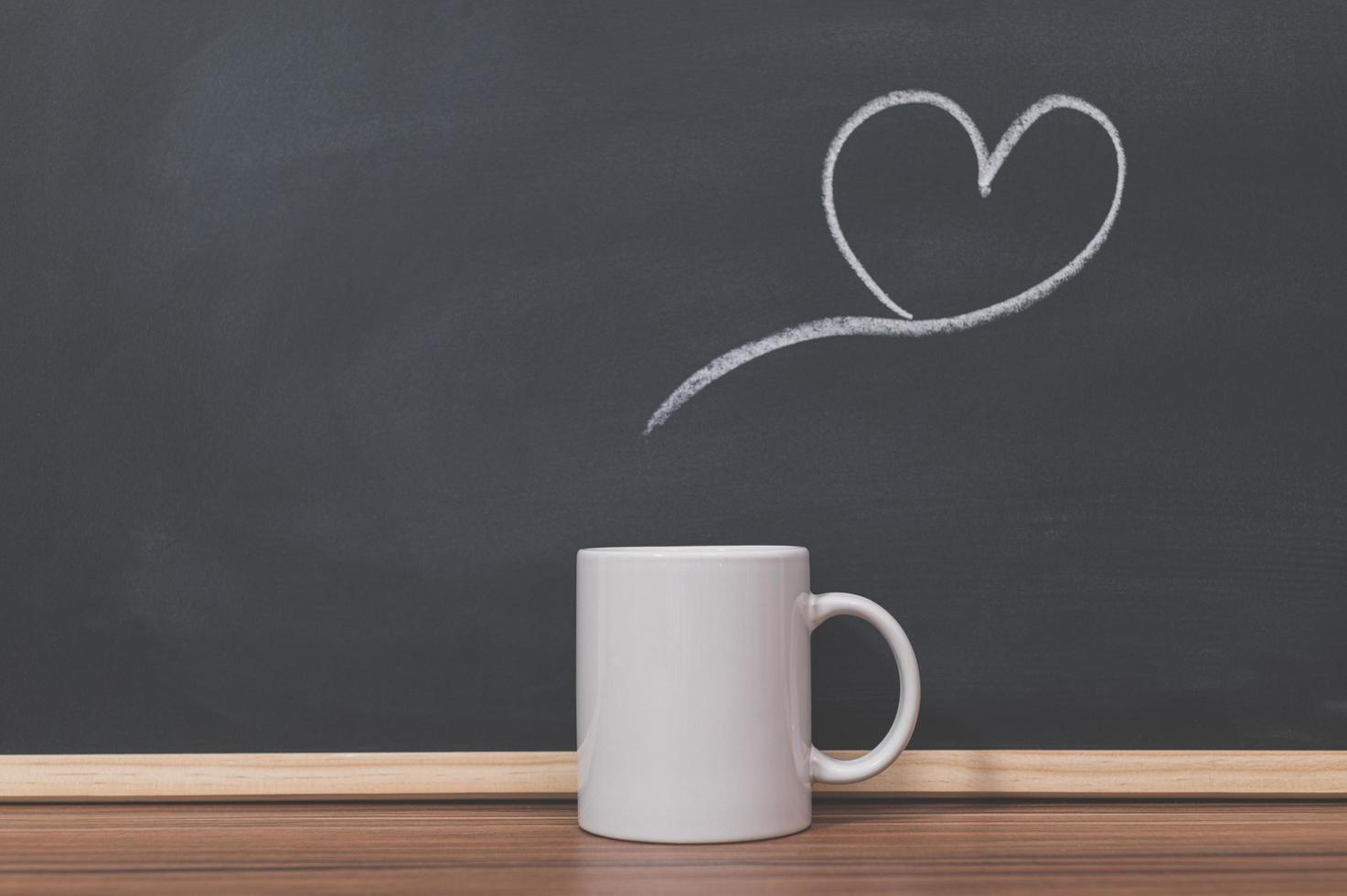 Taza de café y doodle de corazón en la pizarra foto