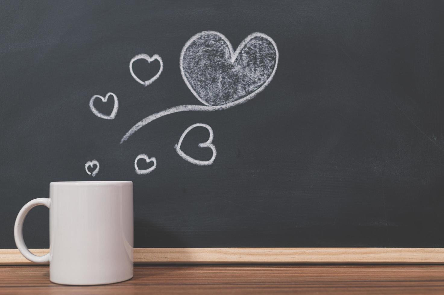 Coffee mug and heart doodle on the blackboard photo