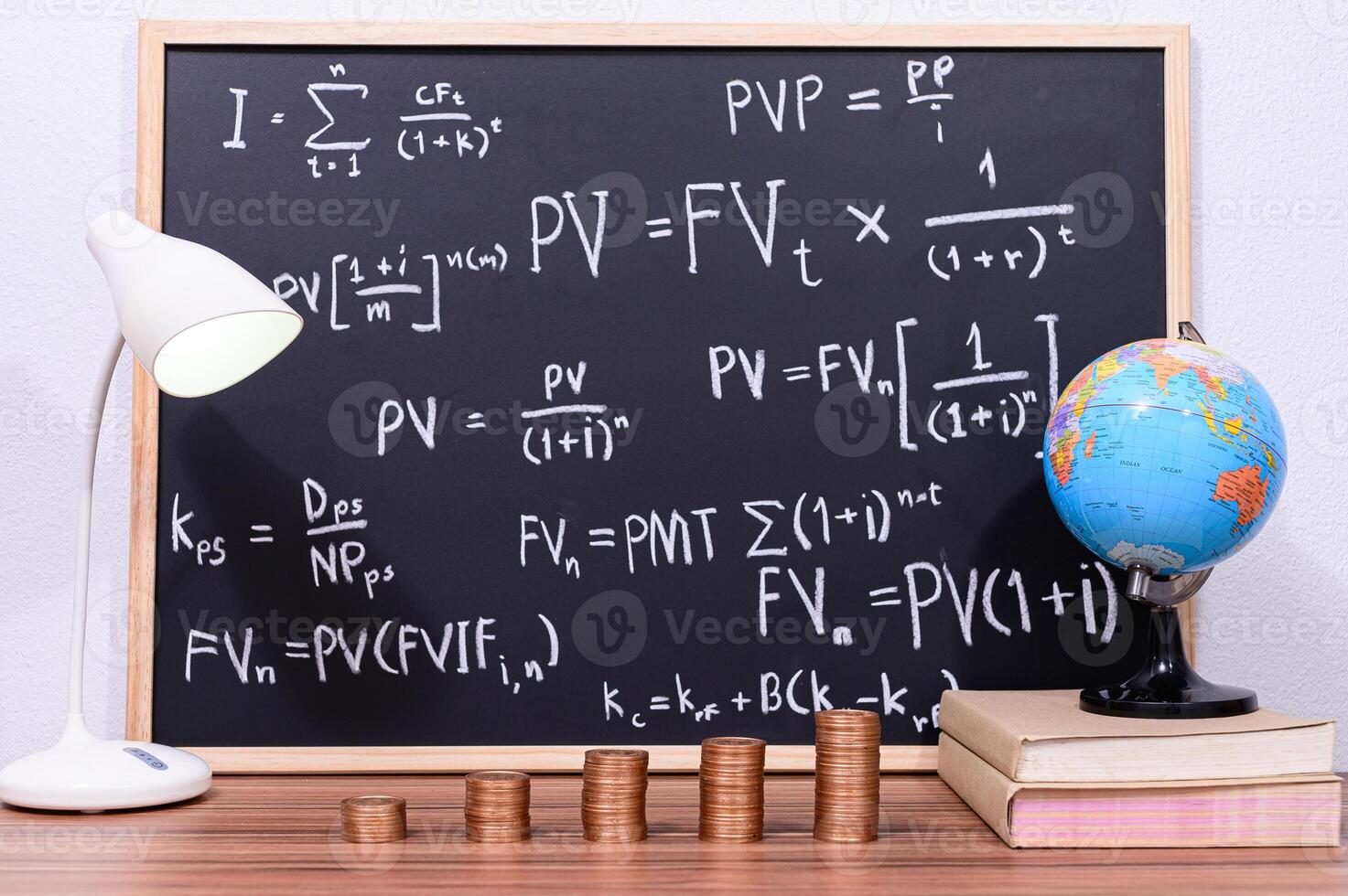 Maths and finance concept on blackboard with coins and globe photo
