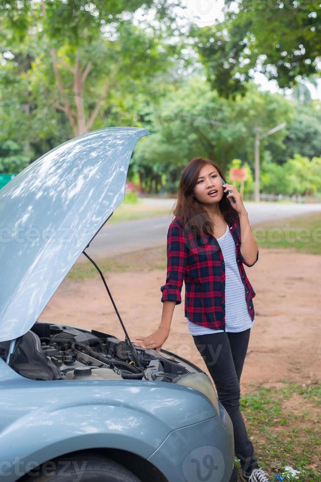 mujer joven con un coche averiado foto