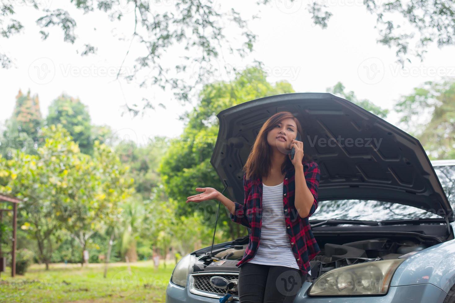 mujer joven con un coche averiado foto