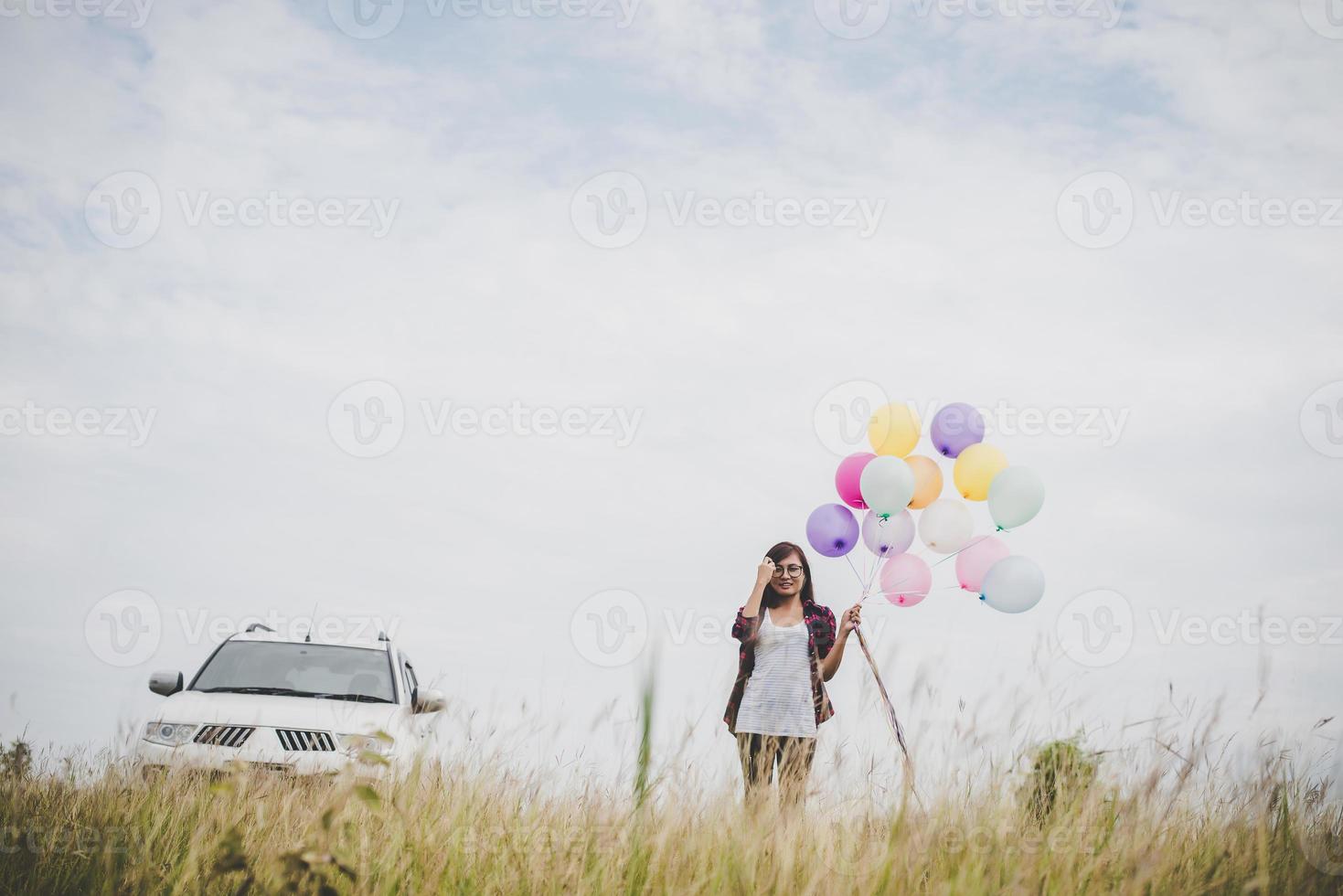 Beautiful young hipster woman holding colorful balloons outdoors photo