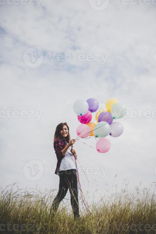 Hermosa joven inconformista sosteniendo globos de colores al aire libre foto