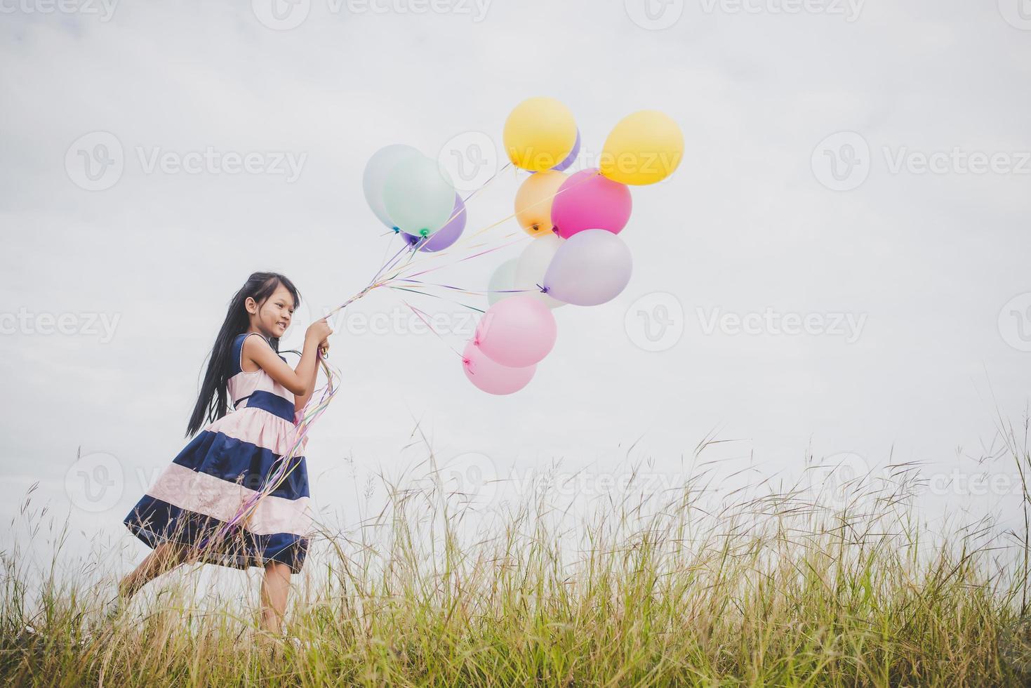 Little girl playing with balloons on meadows field photo