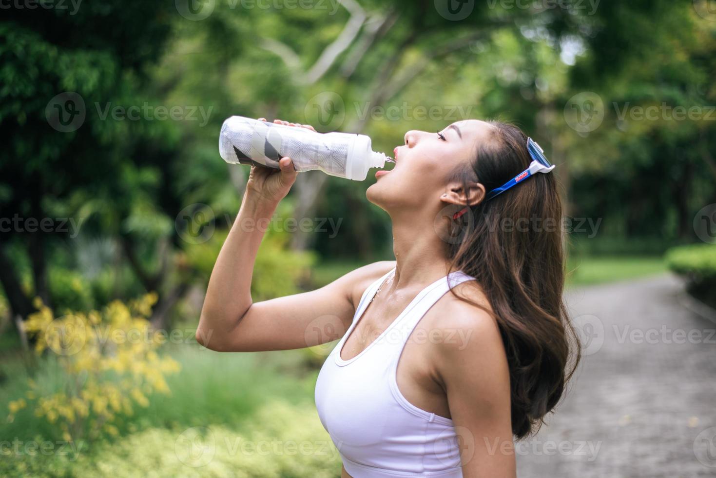 Young healthy woman drinking water after jogging photo