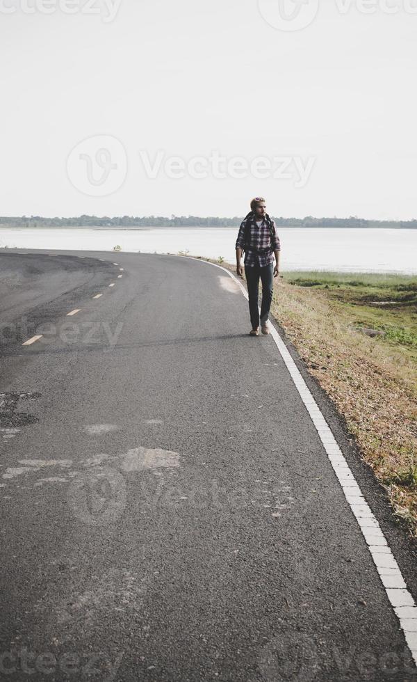 Hombre joven turista caminando por una carretera rural foto