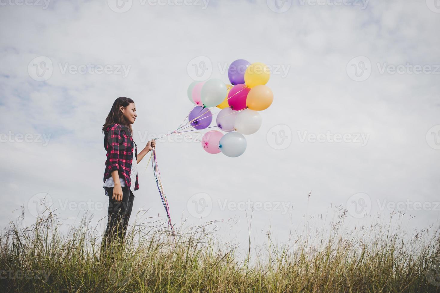 Hermosa joven inconformista sosteniendo globos de colores al aire libre foto