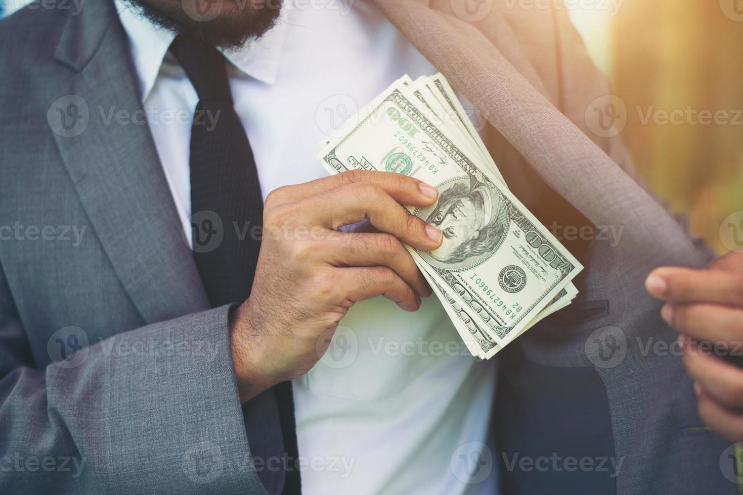 empresario poniendo dinero en su bolsillo foto