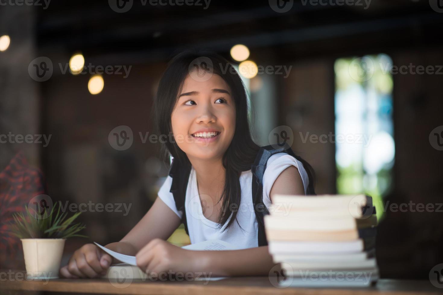 Mujer joven leyendo un libro sentado en el interior de un café urbano foto