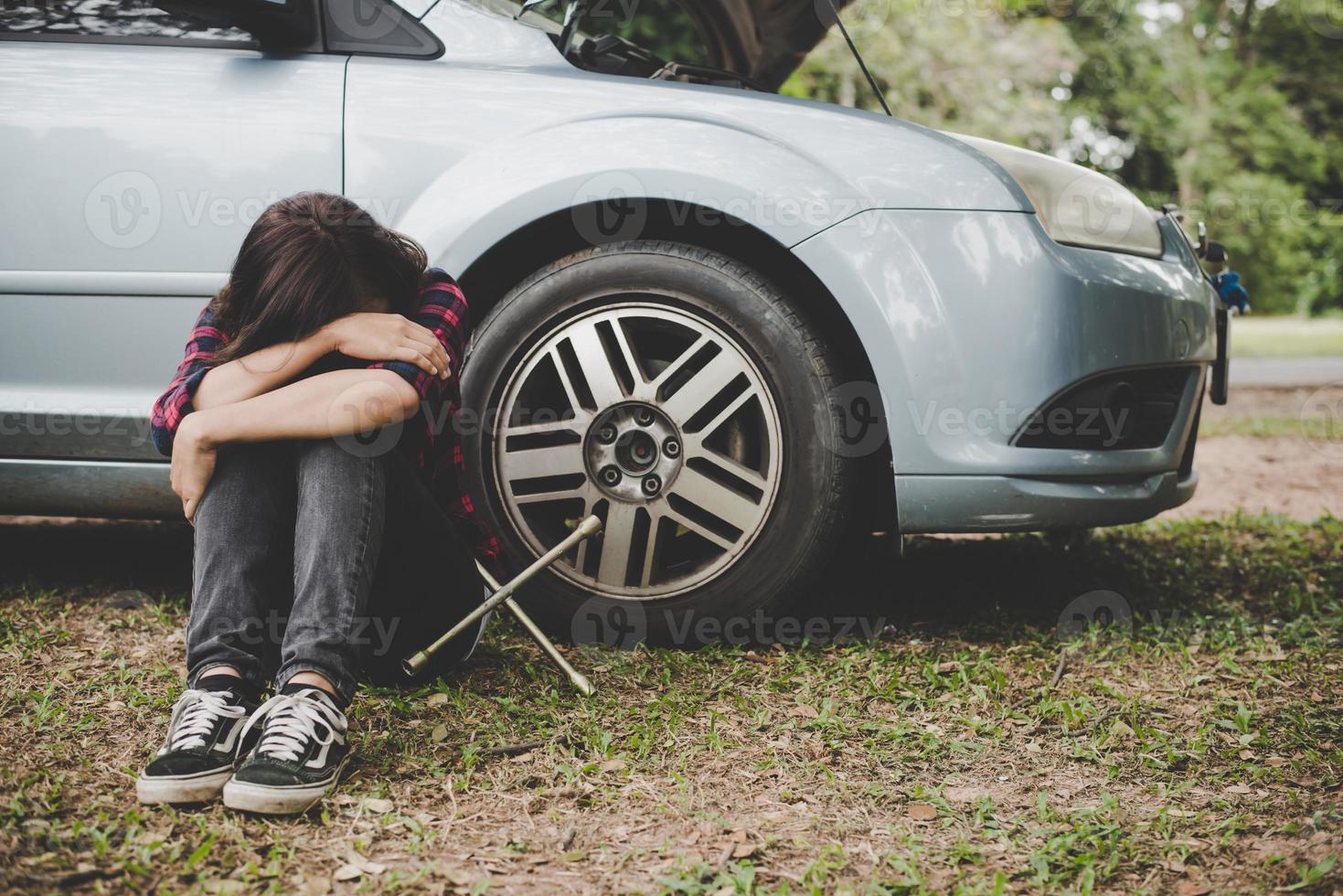 Mujer joven inconformista con un pinchazo en su coche foto