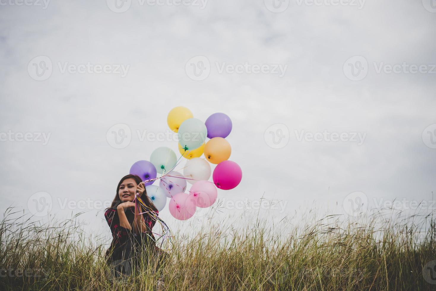 Beautiful young hipster woman holding colorful balloons outdoors photo