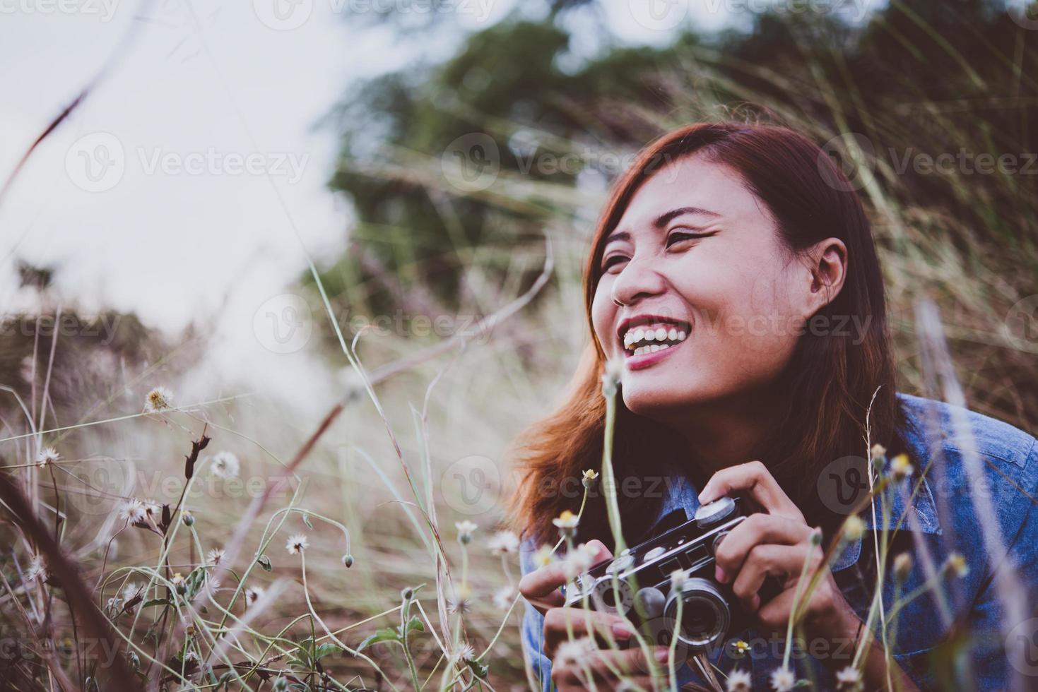 Happy young hipster woman with vintage camera in field photo