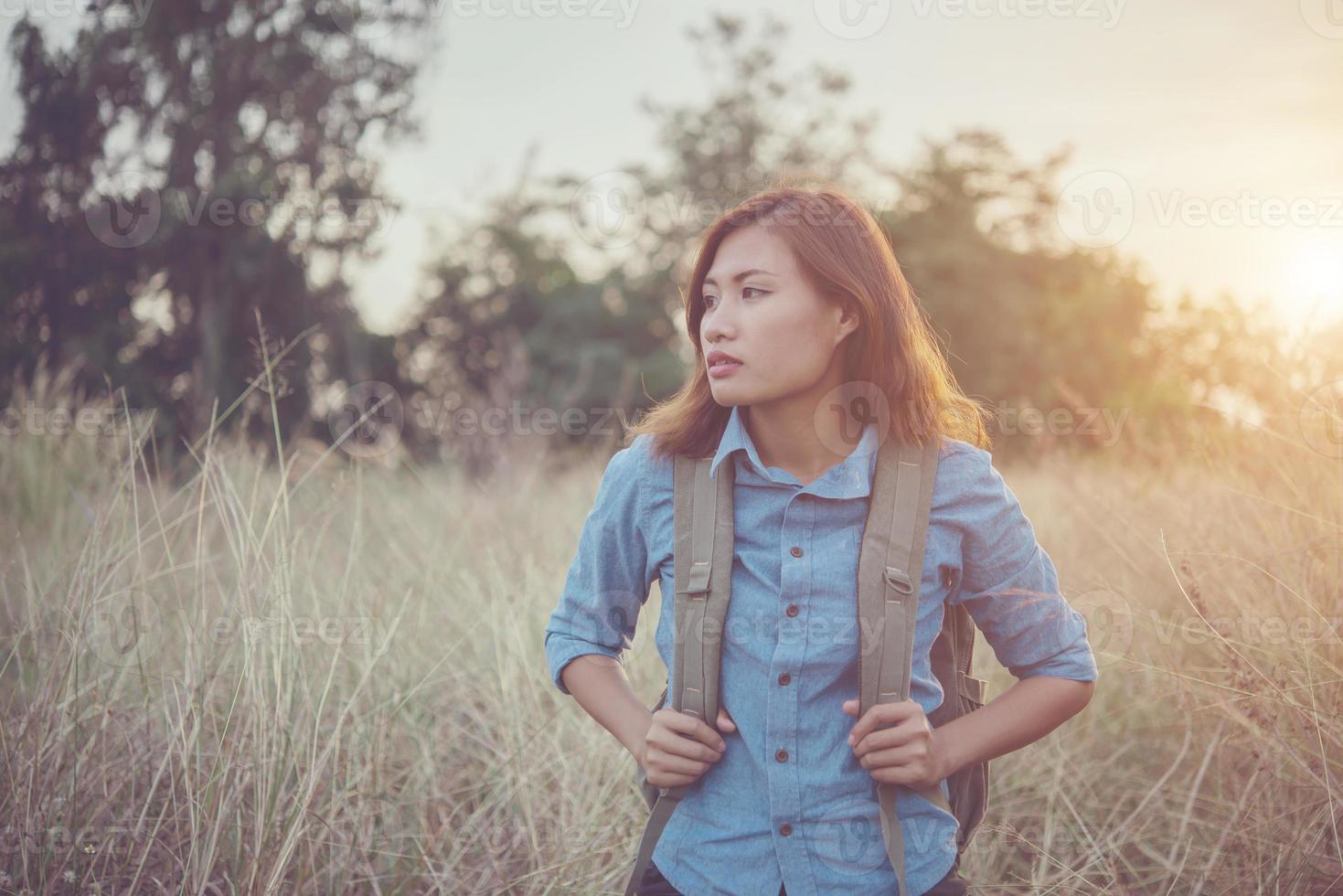 Vintage tone image of a beautiful young hipster woman with backpack in a meadow photo