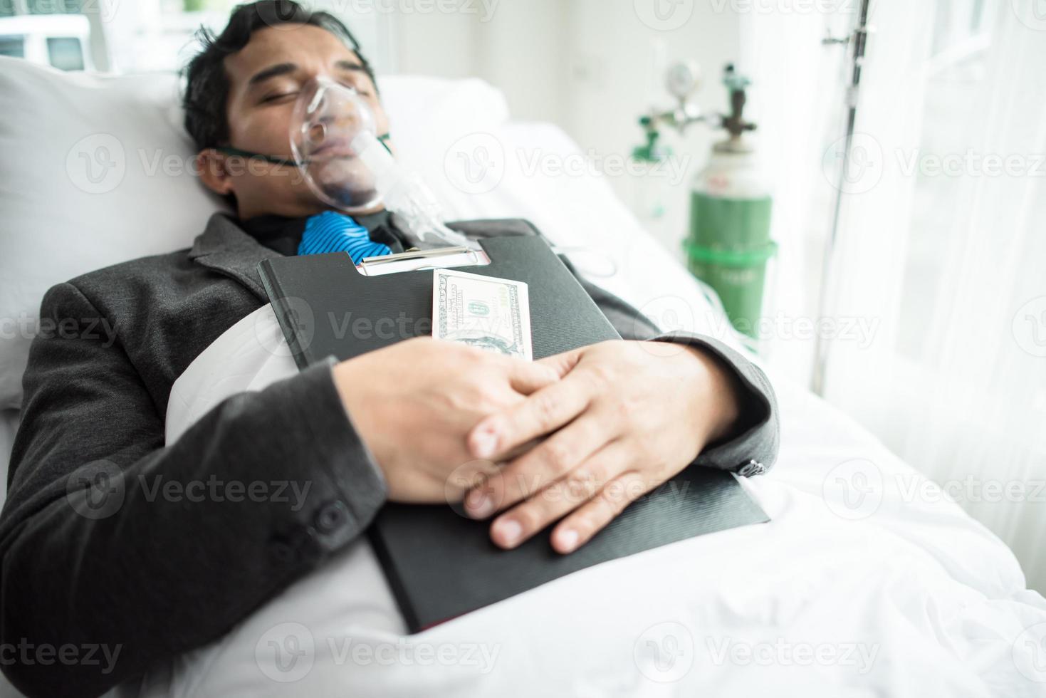 Businessman with oxygen mask working from bed photo