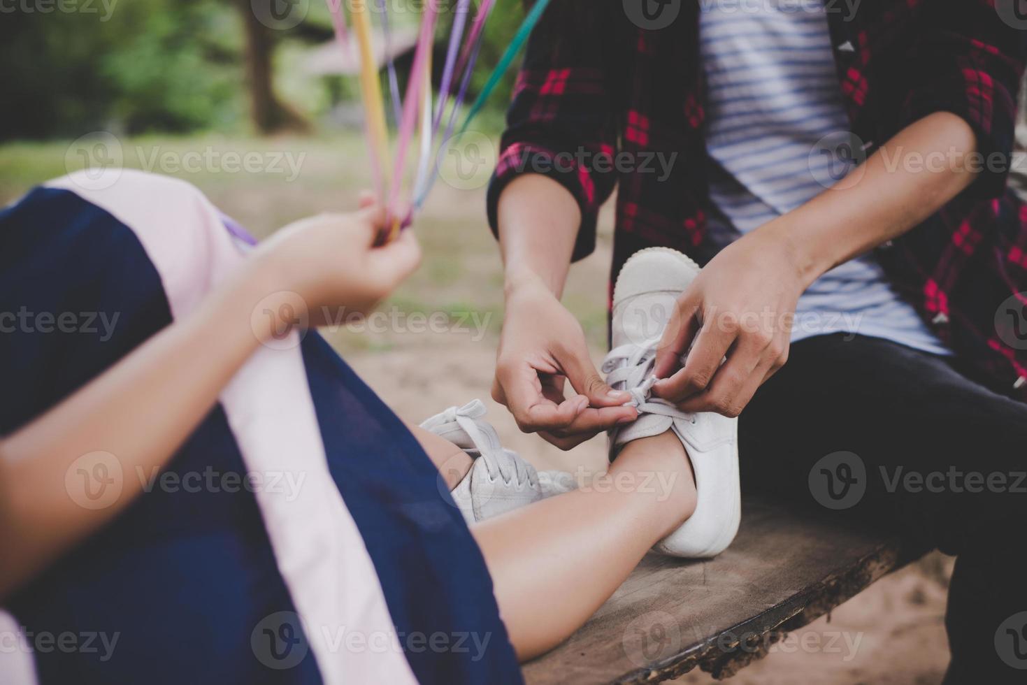 Mother ties shoe for her daughter while sitting on swing photo