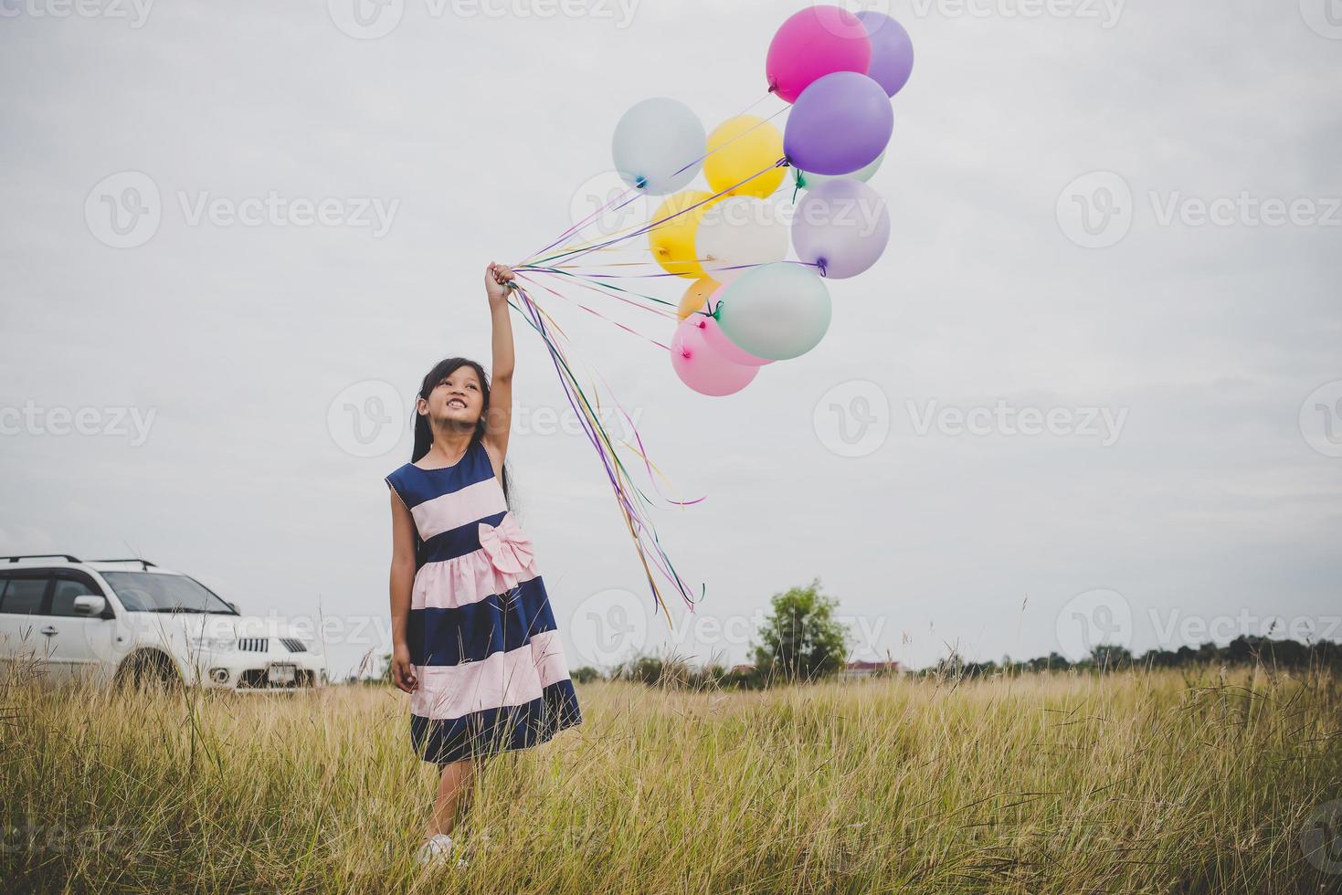 niña jugando con globos en el campo de prados foto
