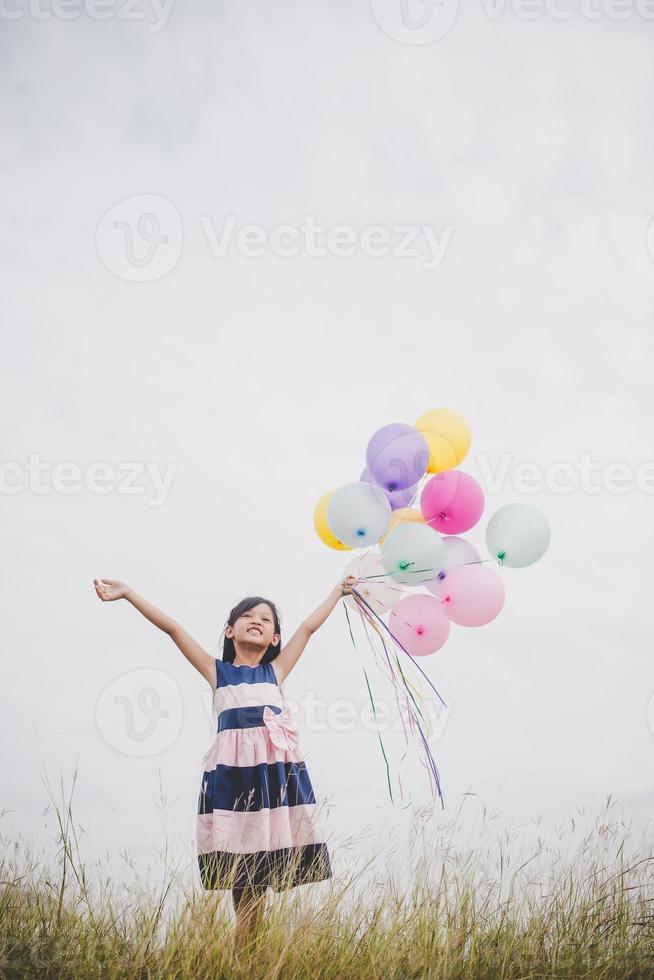 Little girl playing with balloons on meadows field photo