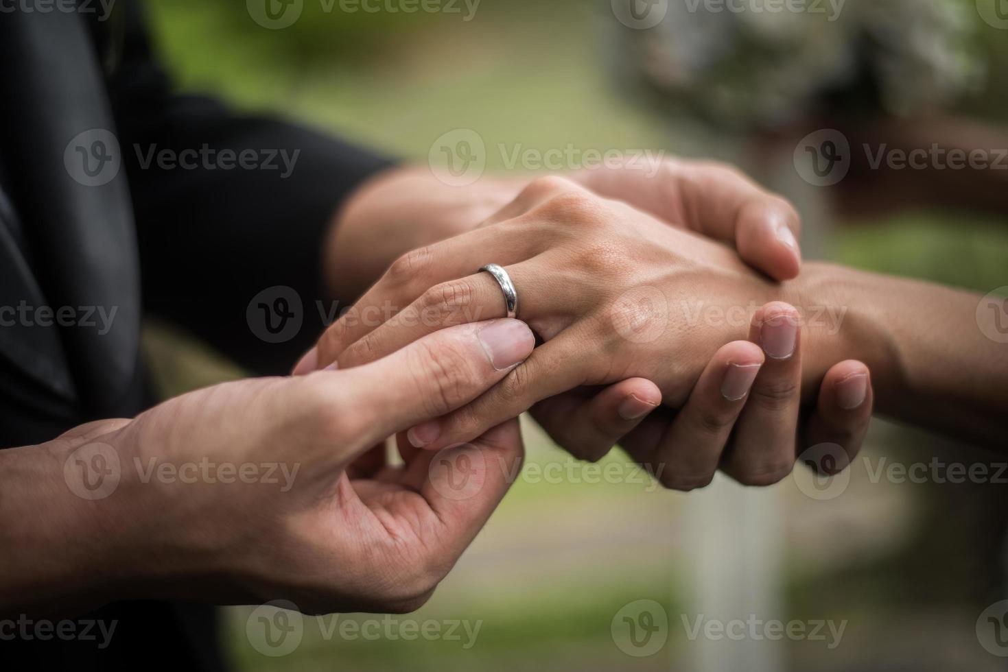 Close-up of groom putting ring on bride photo