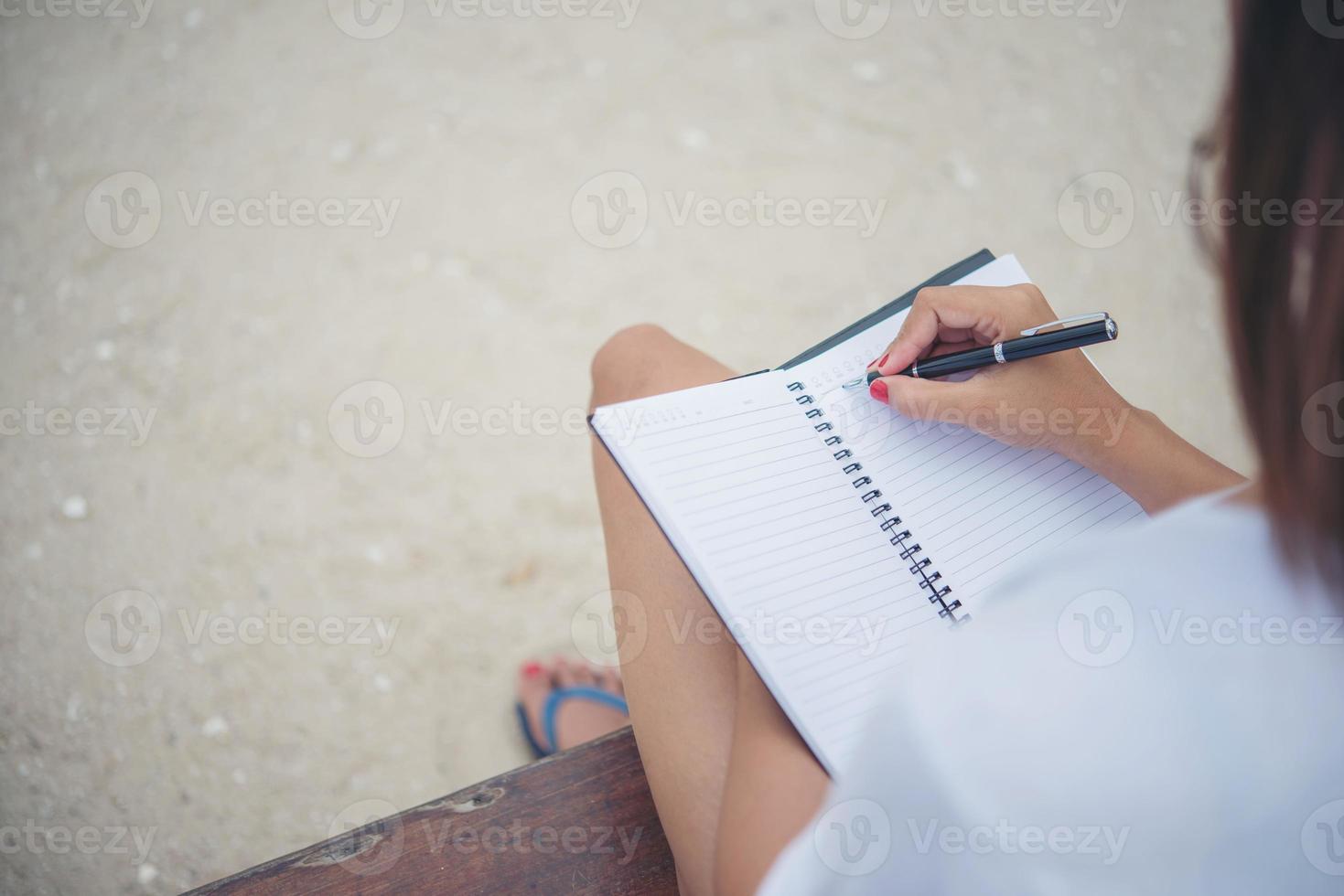 Hermosa joven en un columpio escribiendo en su bloc de notas foto