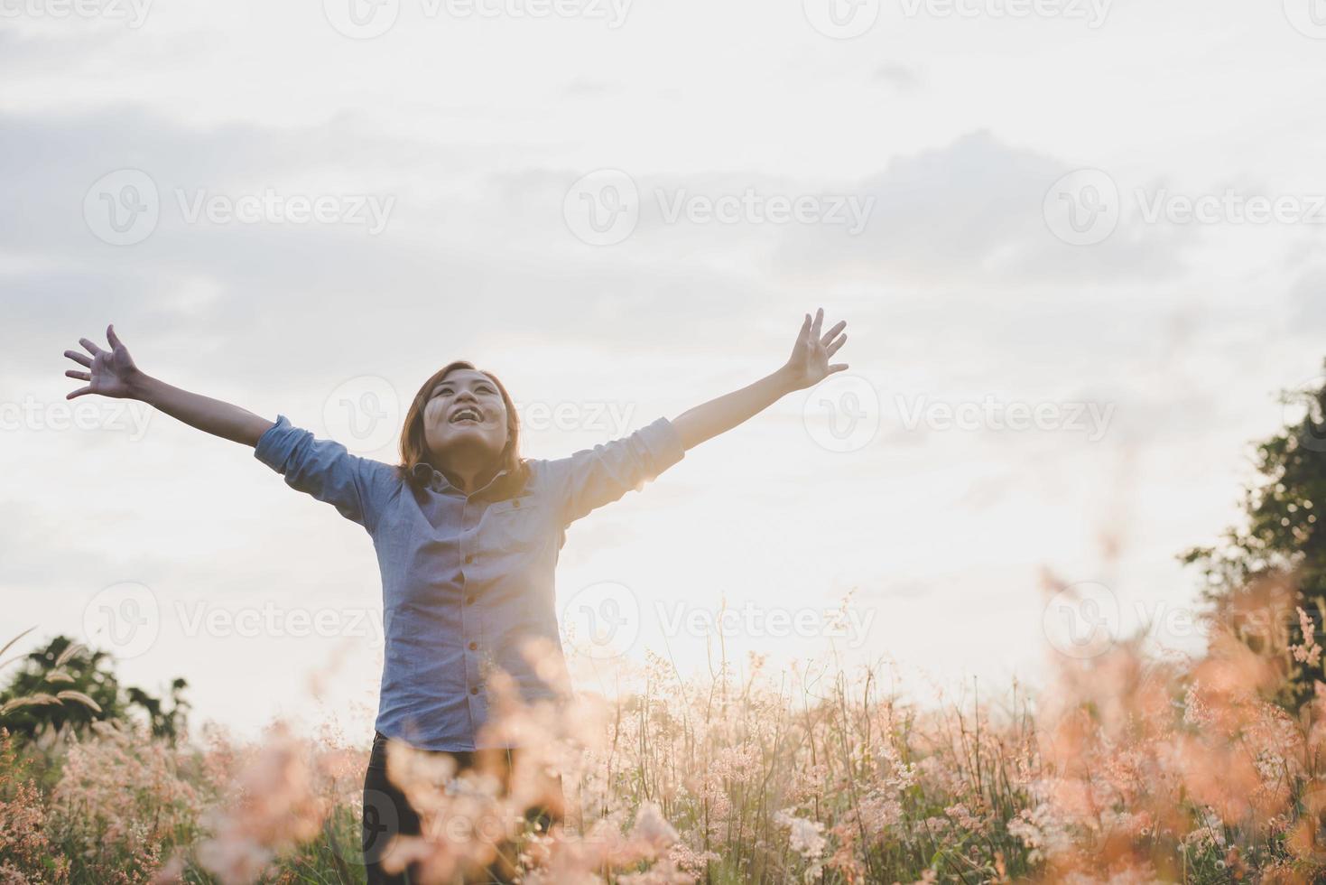 Young beautiful woman stretches her arms in the air in a field photo