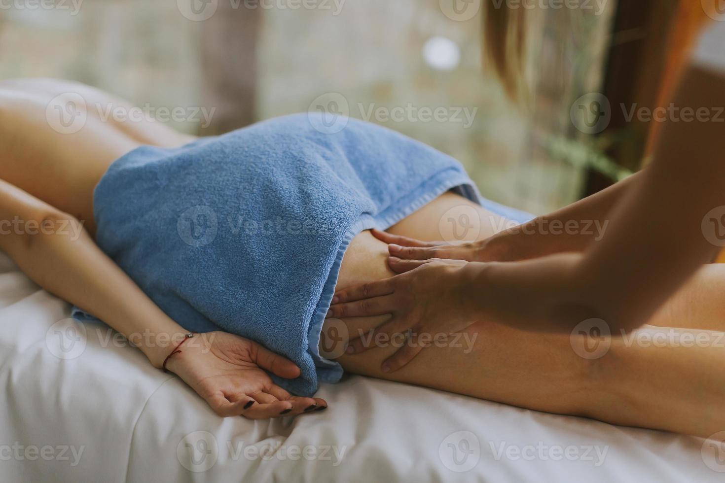 Hermosa joven acostada y con masaje de piernas en el salón de spa durante la temporada de invierno foto