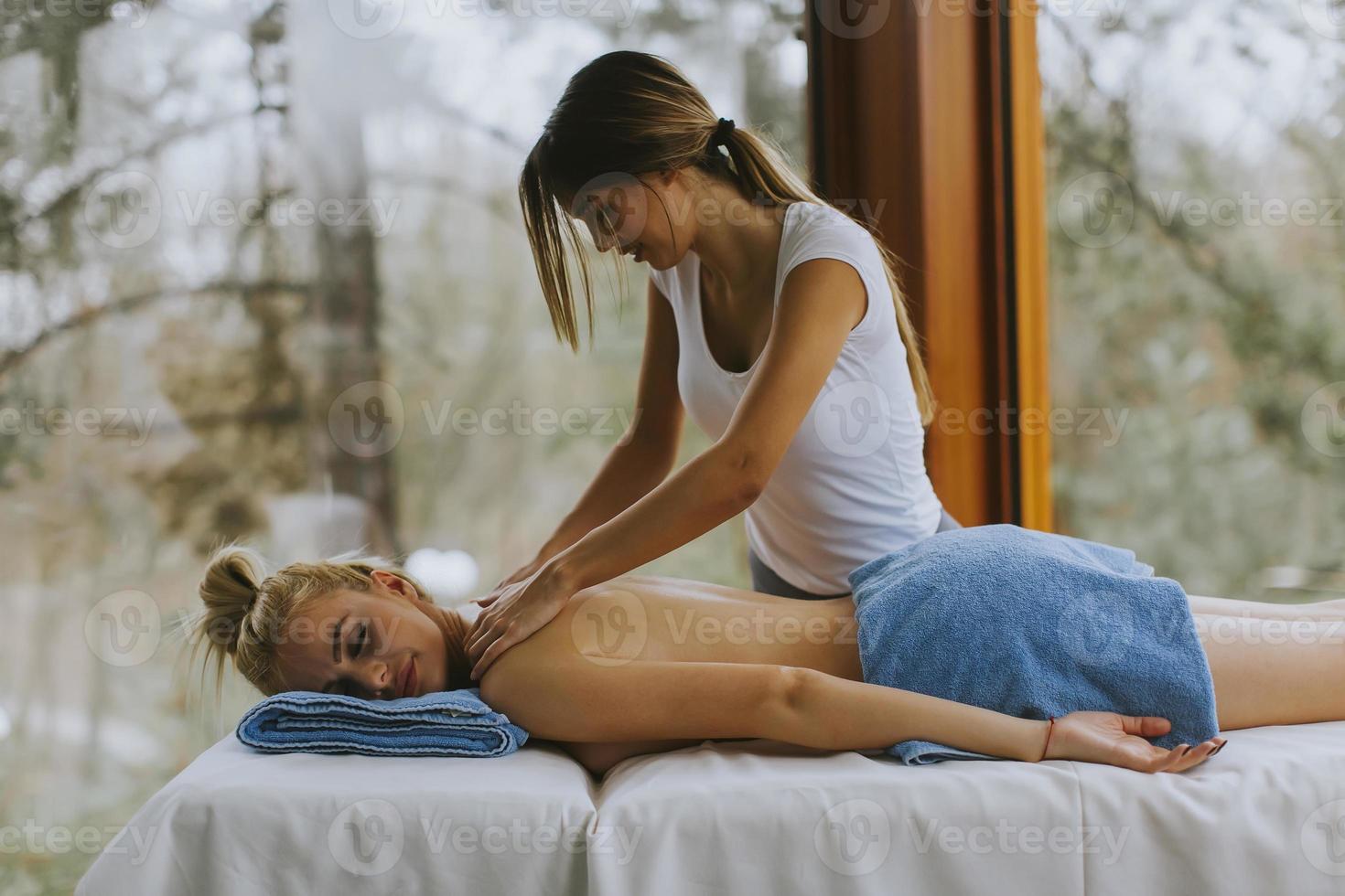 Beautiful young woman lying and having neck massage in spa salon during winter season photo