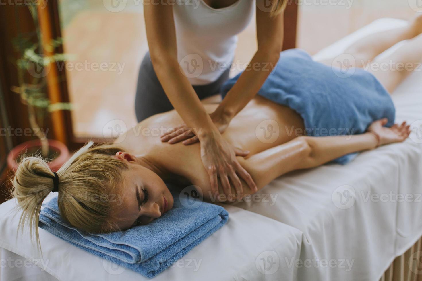 Hermosa joven acostada y con masaje de hombros en el salón de spa durante la temporada de invierno foto