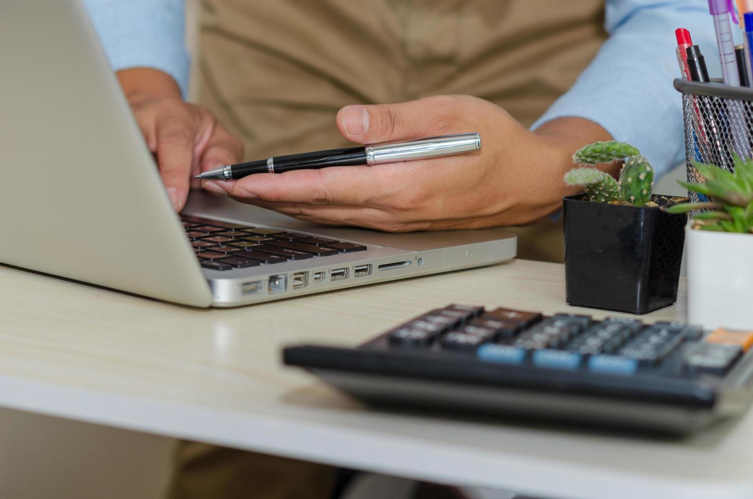 A businessman using a computer to find information while holding a pen photo