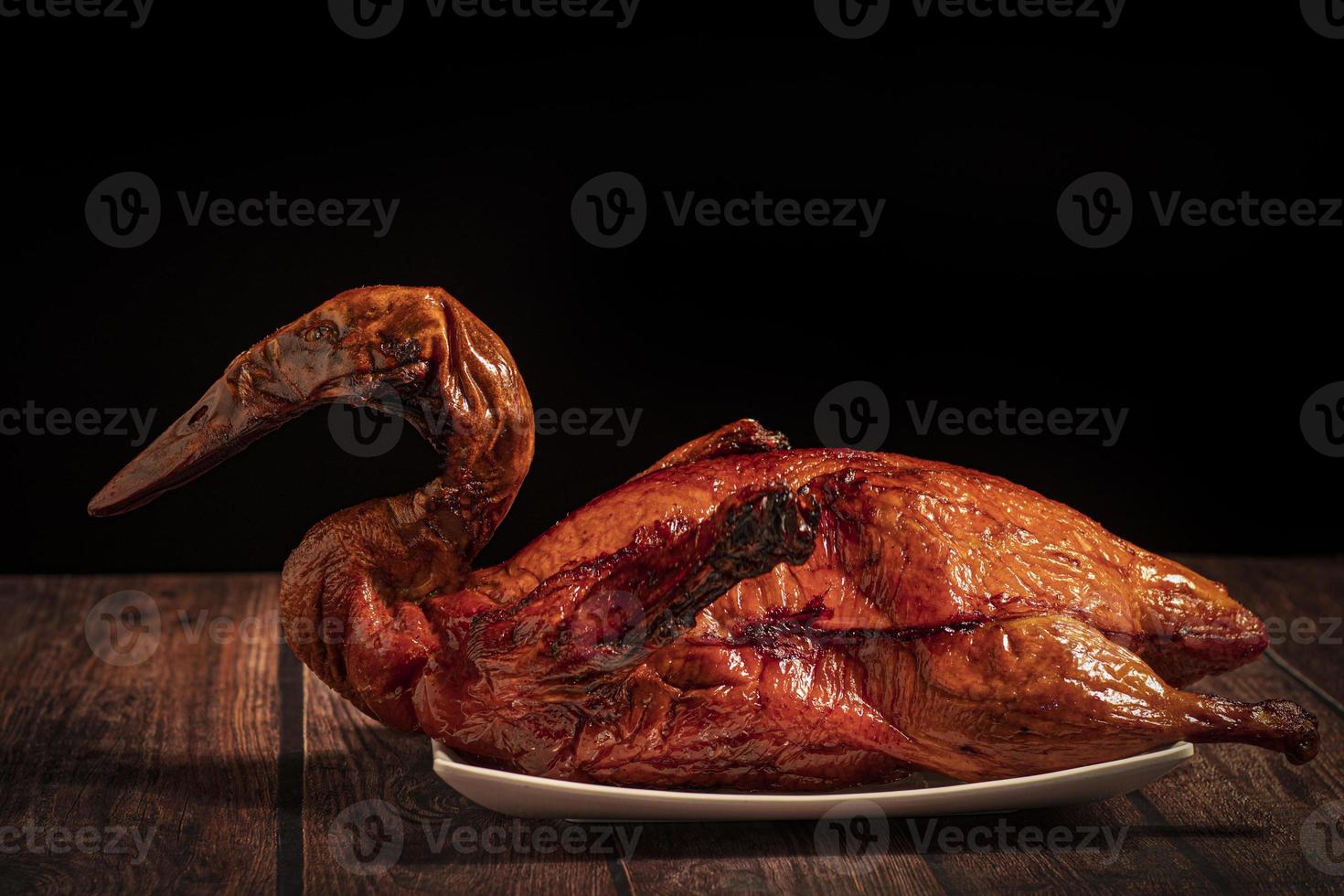 Whole roast duck on white plate on wooden table photo