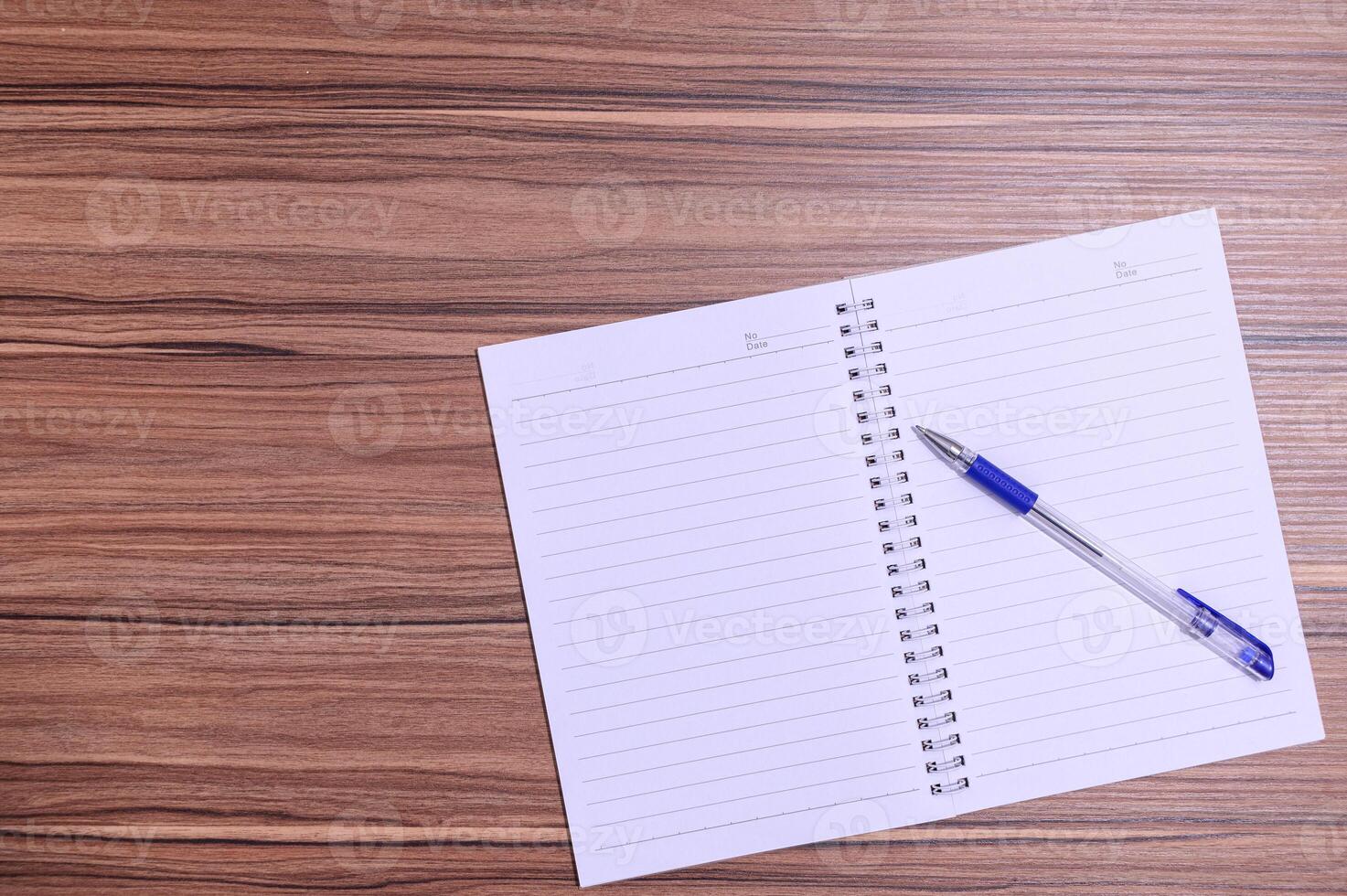 Notebook with pen on wooden table top view photo