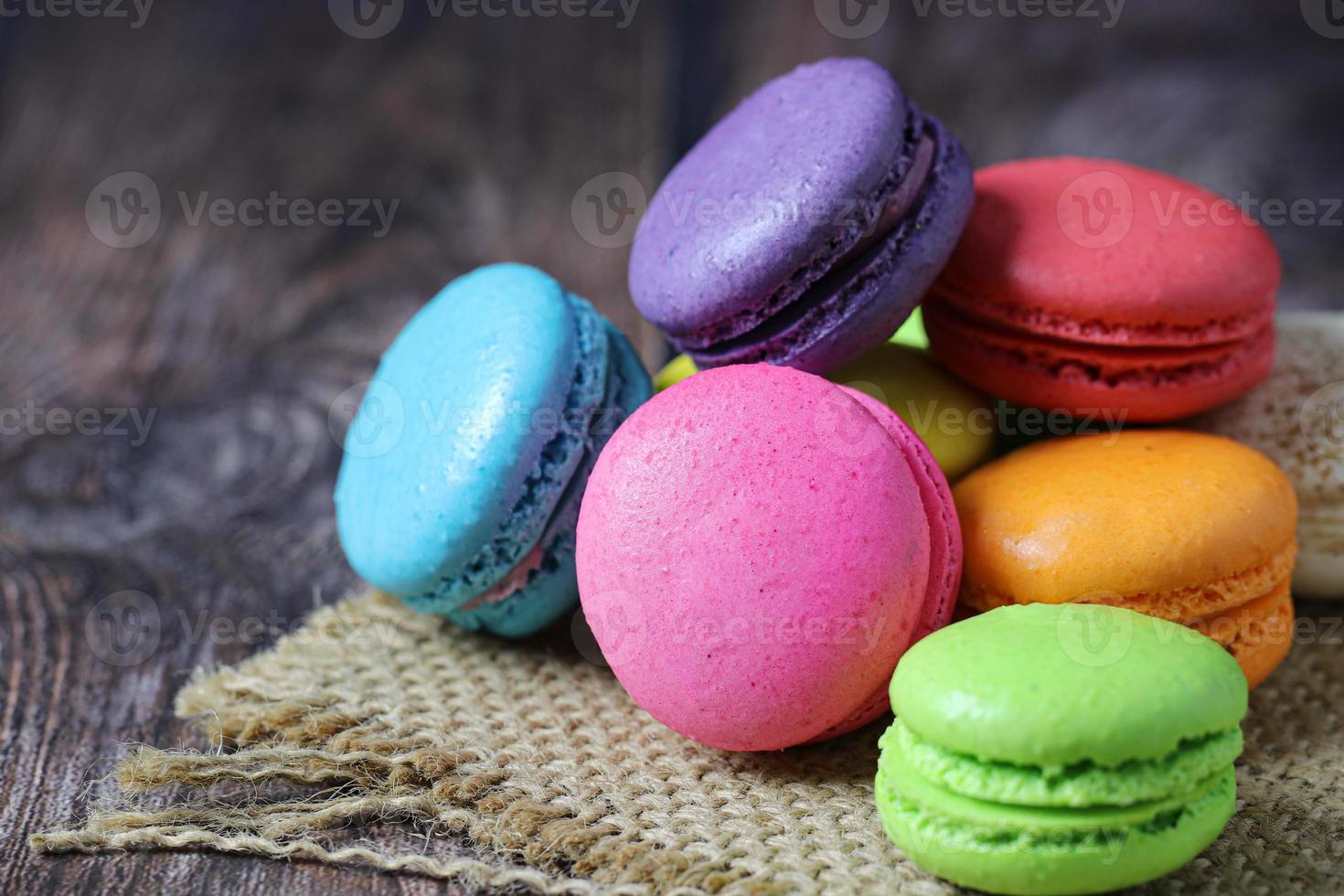 Colorful macarons on burlap mat on wooden table photo