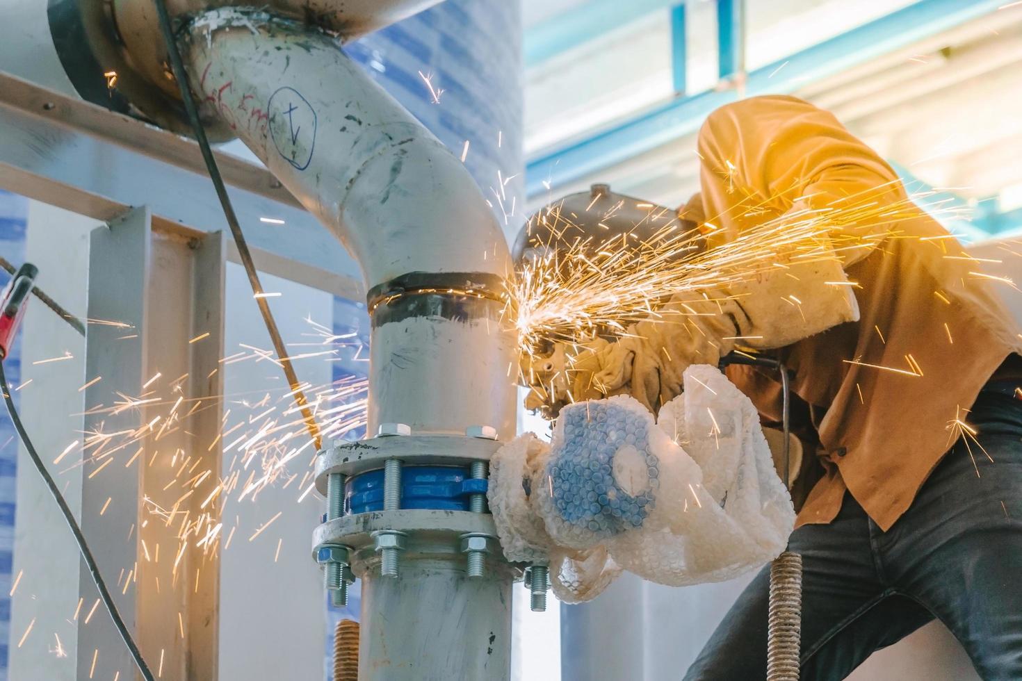 Heavy industry worker grinding steel pipe photo