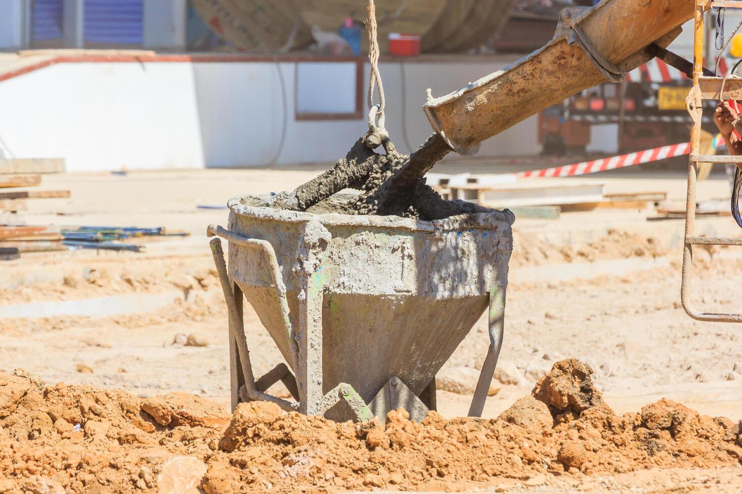 Concrete mixer truck pouring liquid concrete into the tower crane bucket photo