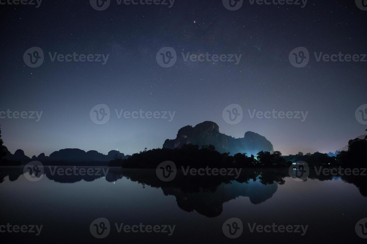 cielo estrellado y montañas reflejadas en el agua foto