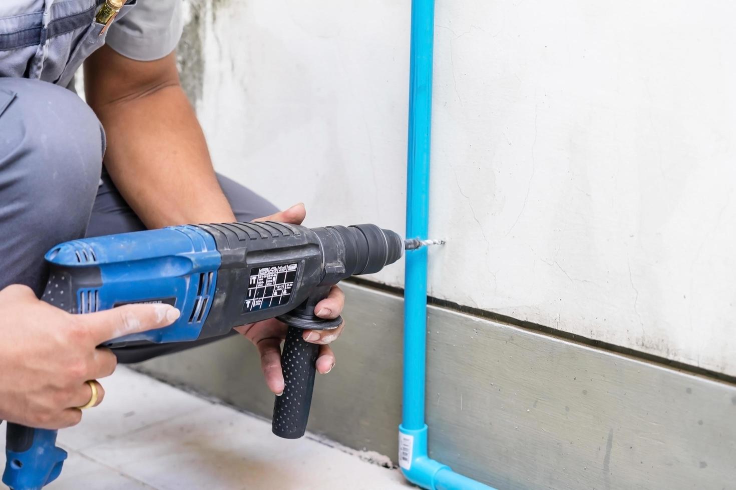 Worker using a drilling power tool on construction site photo