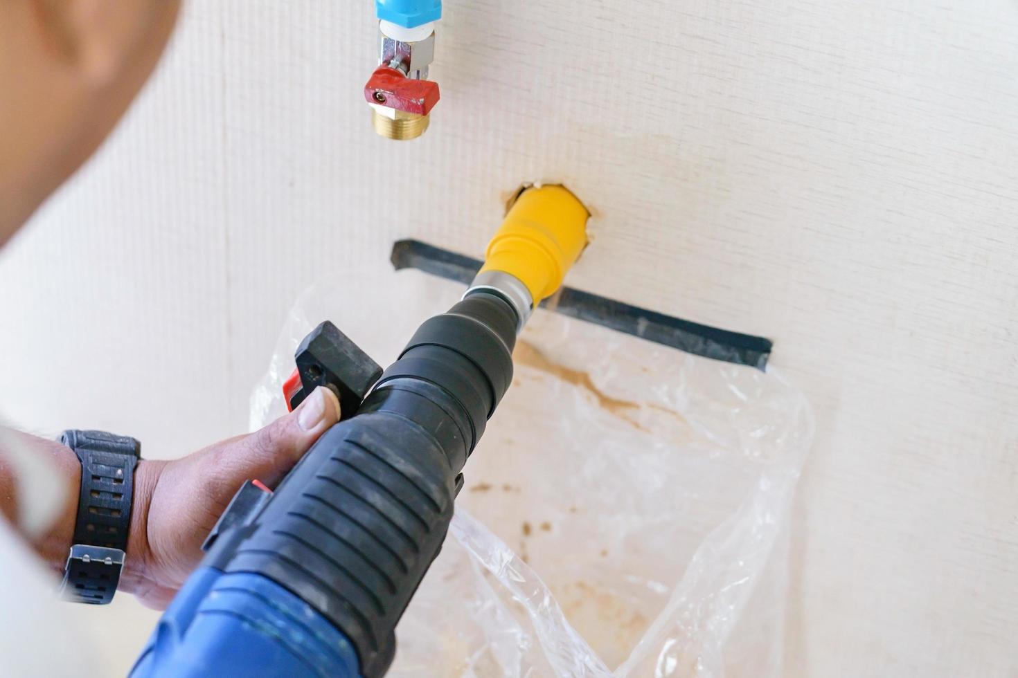 Worker using a drilling power tool on construction site photo